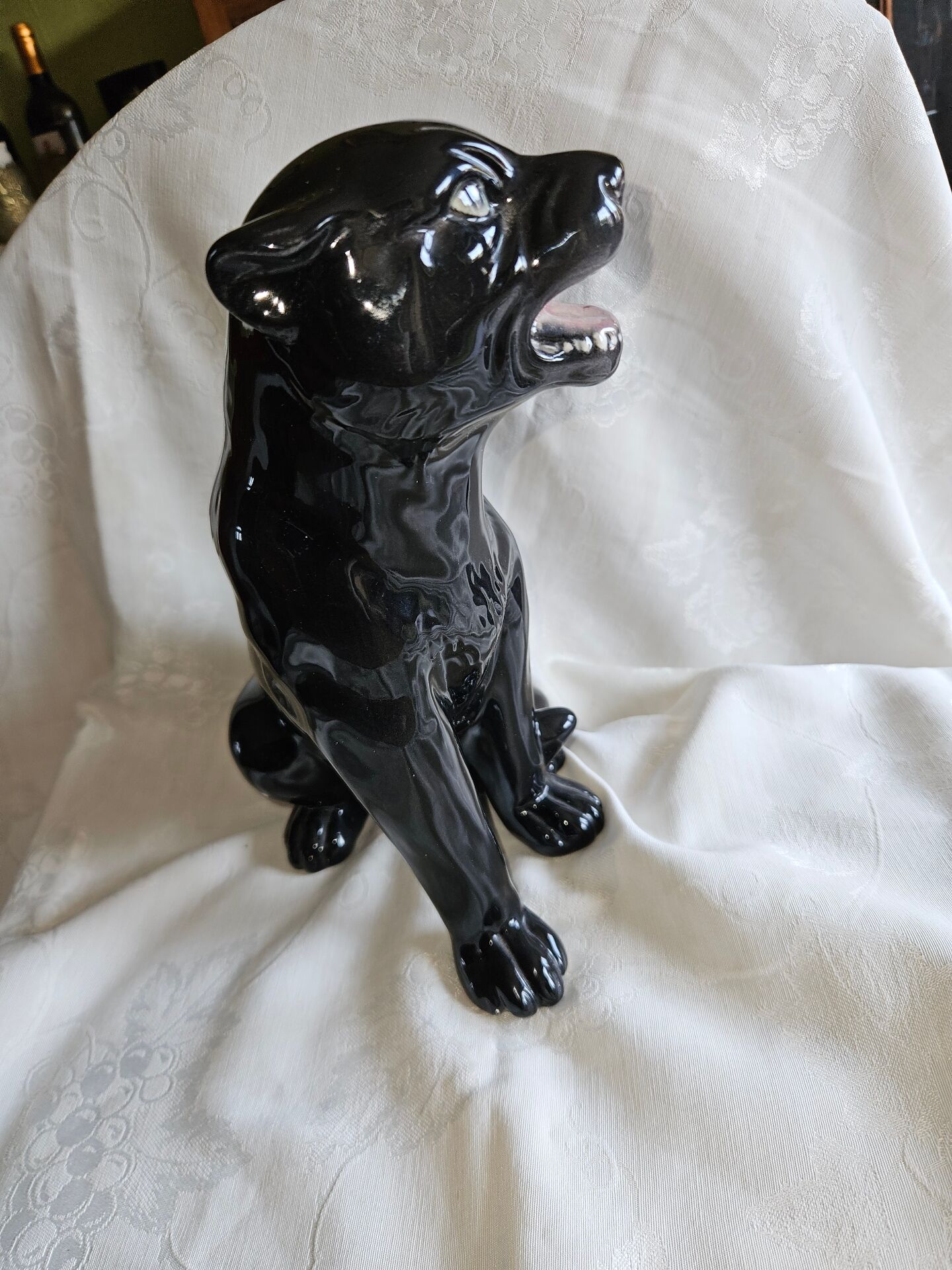 Statue of a roaring panther/leopard sitting in black glazed ceramic.