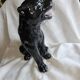 Statue of a roaring panther/leopard sitting in black glazed ceramic.