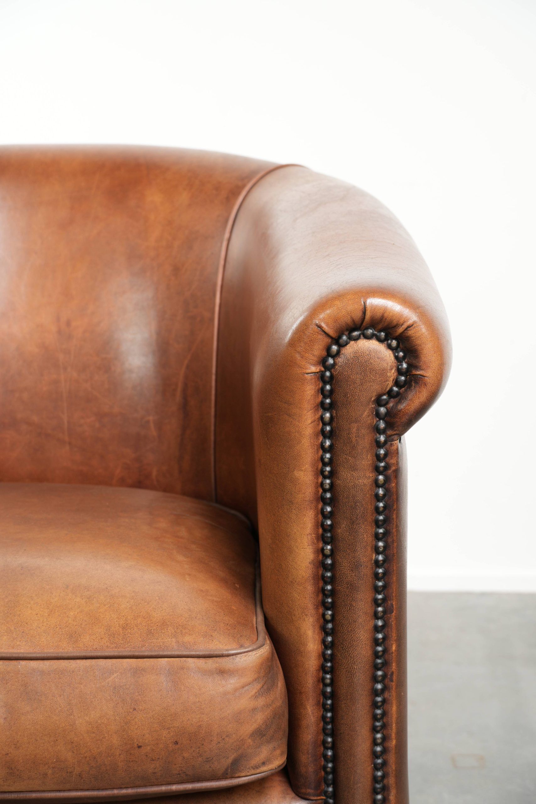 Sheepskin club armchair with a cognac colour finished with decorative nails