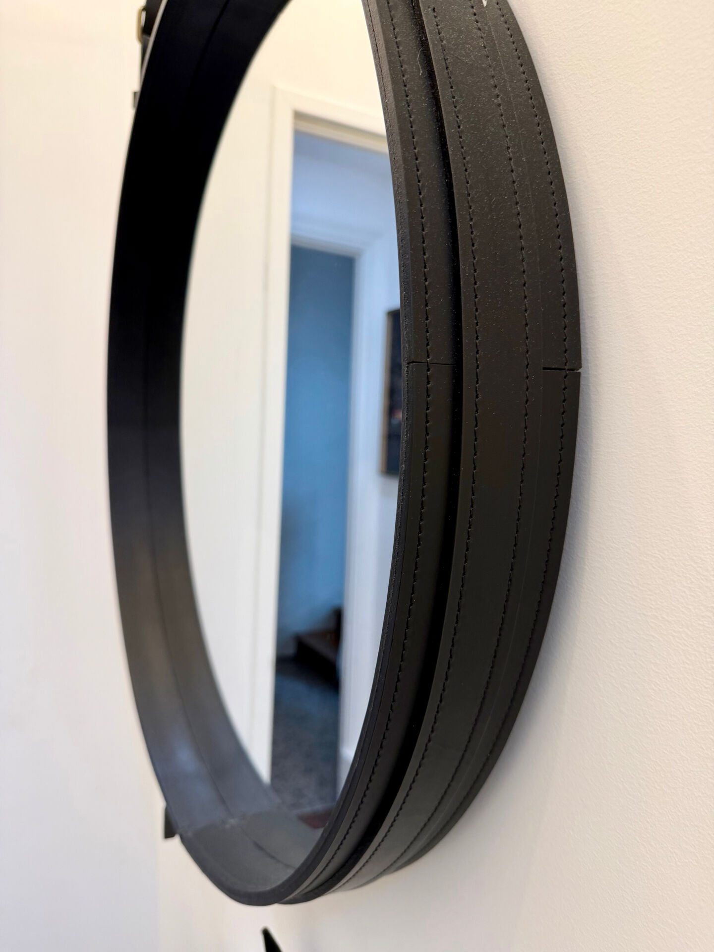 Round mirror covered in black leather in the style of Jacques Adnet.