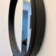 Round mirror covered in black leather in the style of Jacques Adnet.