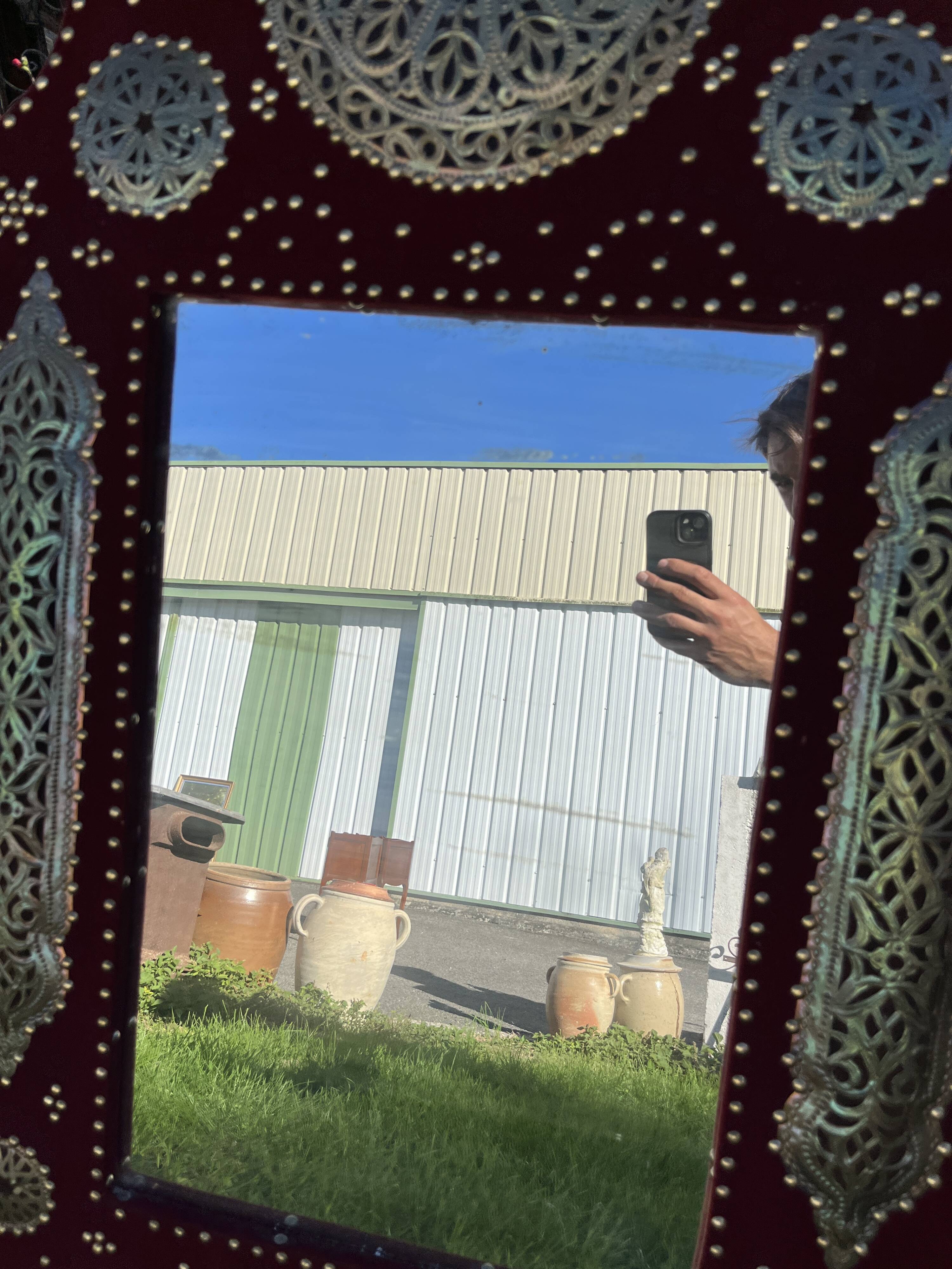 Large oriental mirror with embossed brass decoration on a red velvet background