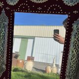 Large oriental mirror with embossed brass decoration on a red velvet background