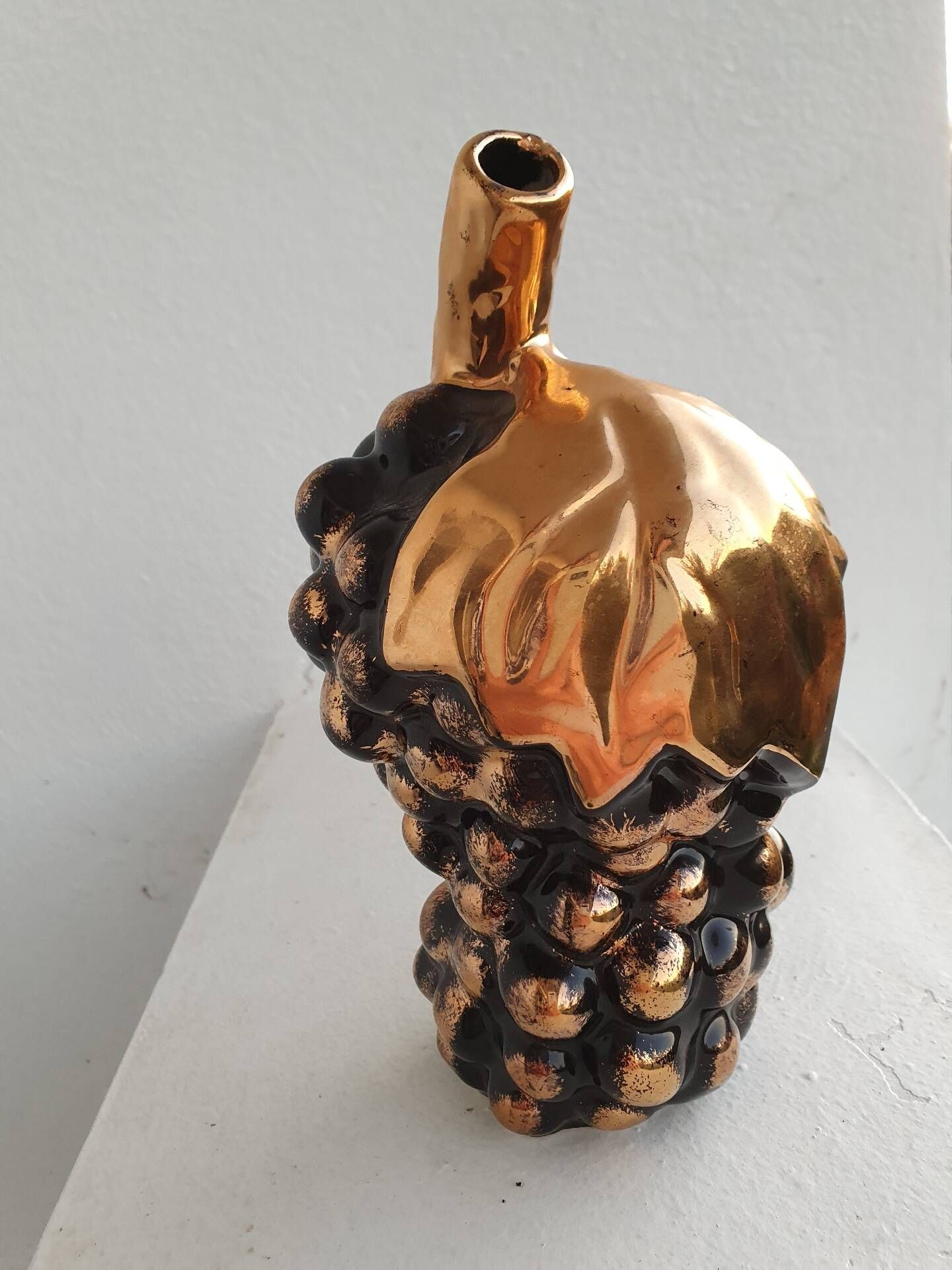 Beautiful black and gold ceramic bottle in the shape of a bunch of grapes.