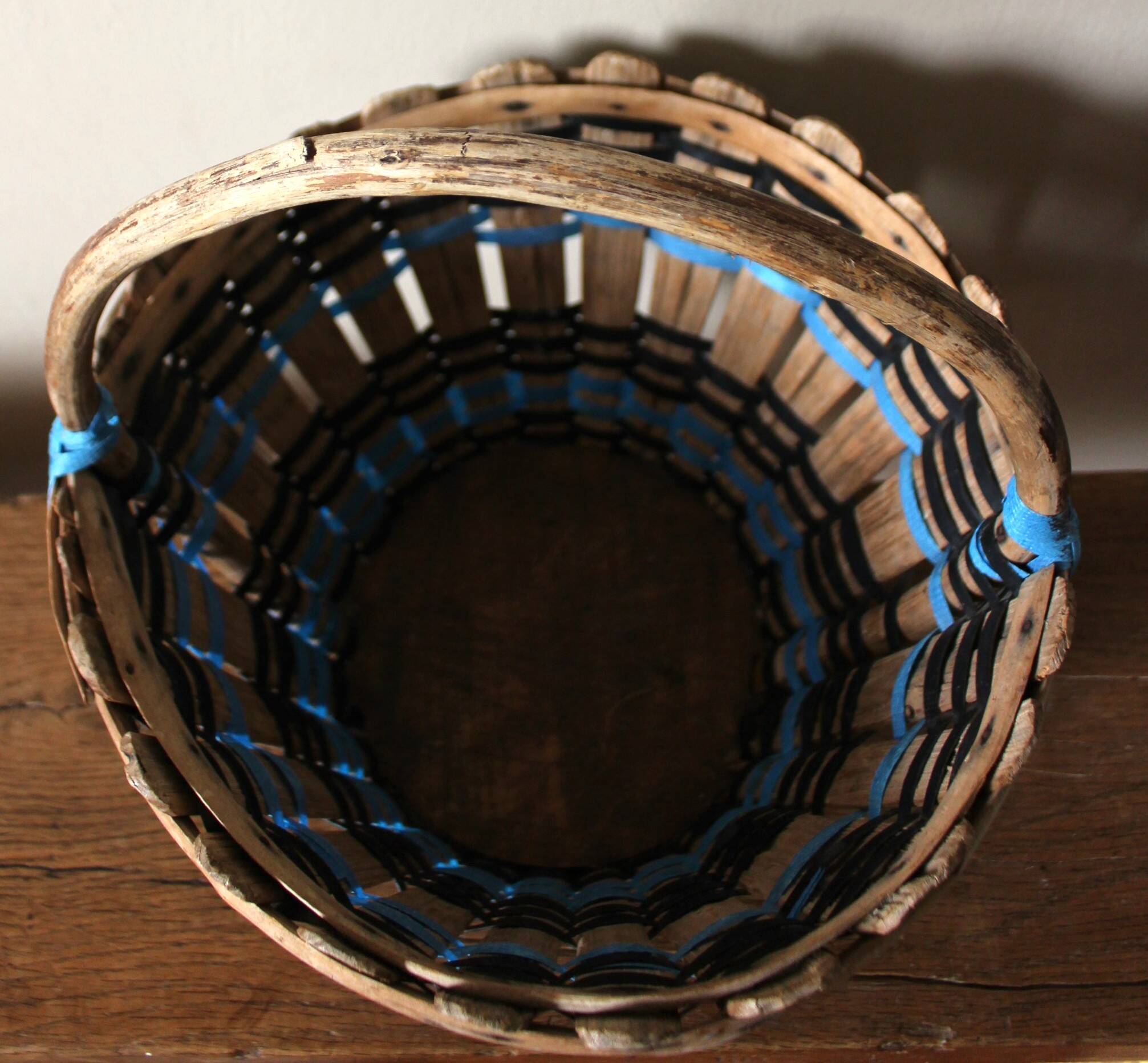 Vintage wooden basket with round handle, blue and black weaving.