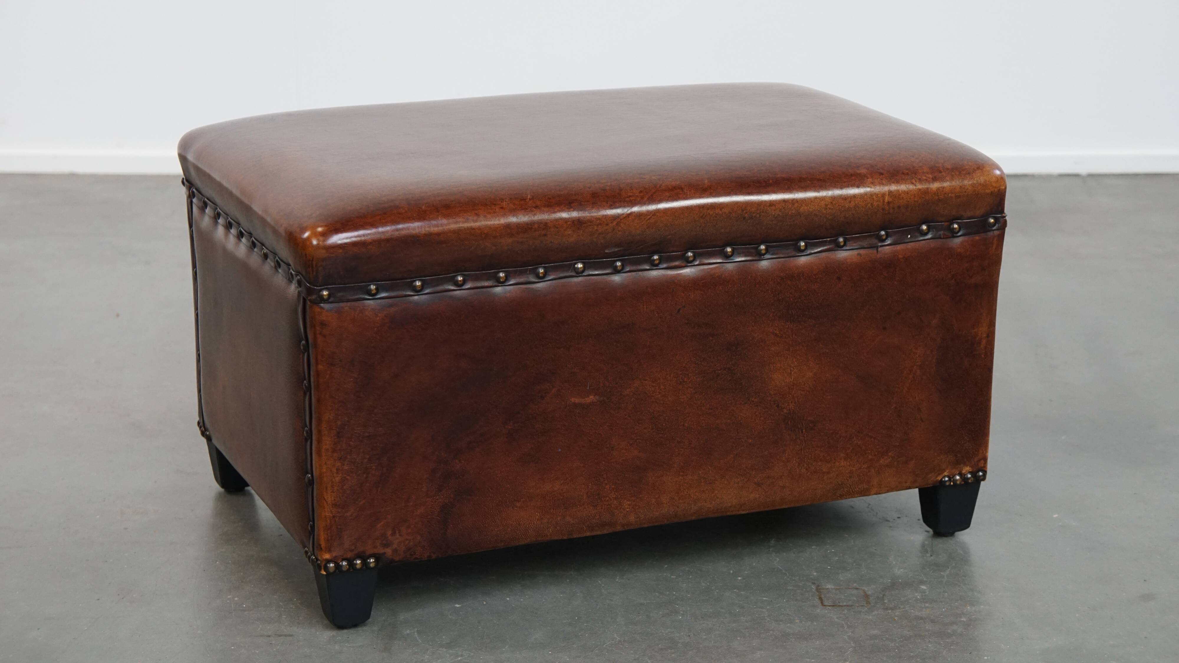 Cognac-colored sheepskin stool with decorative studs