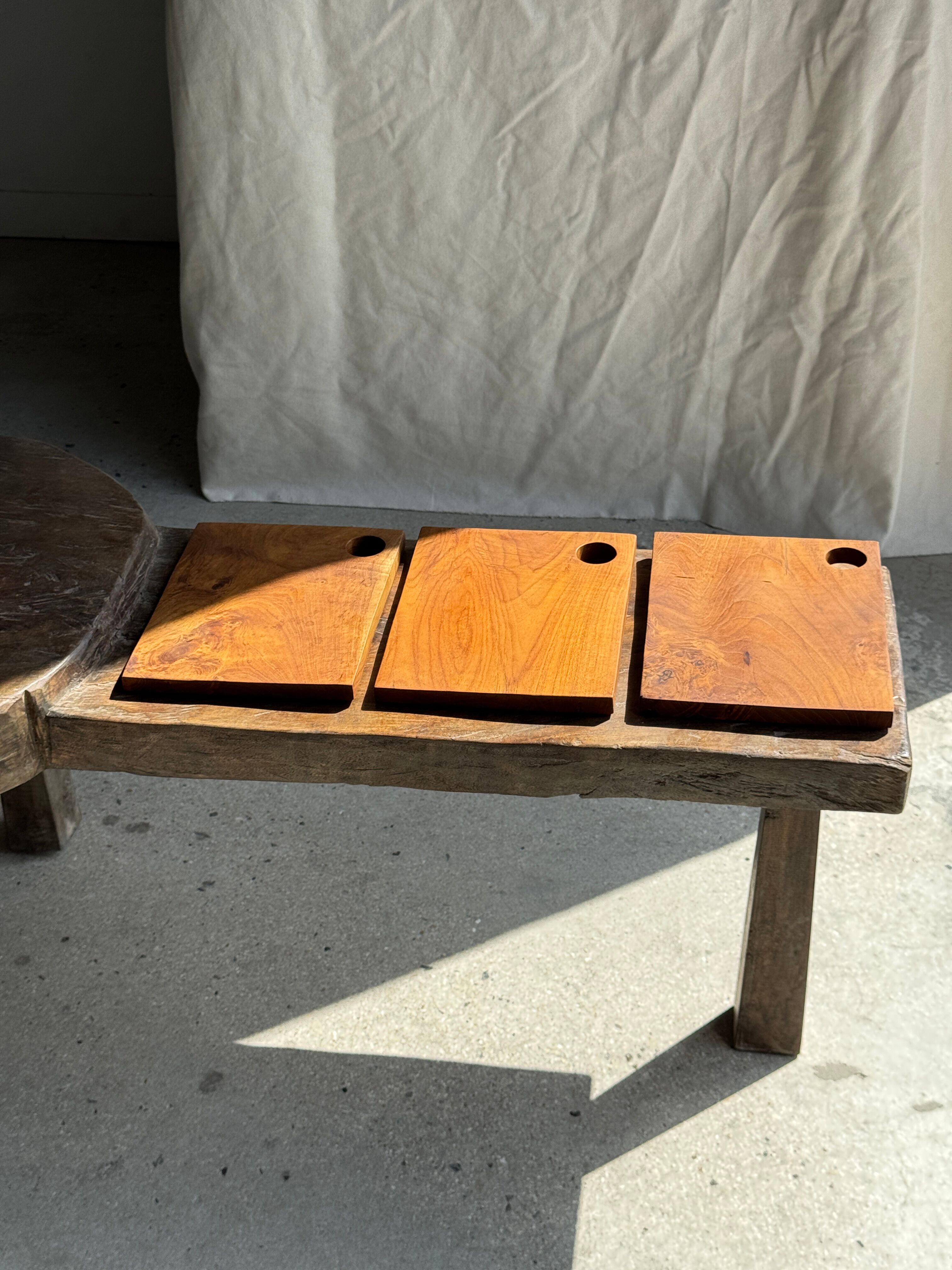 Small rectangular teak monoxyle cutting board with a circular handle.