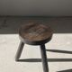 Small brutalistic tripod stool in dark wood tapered feet circular seat