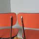 Chairs in red-orange formica and chrome metal.