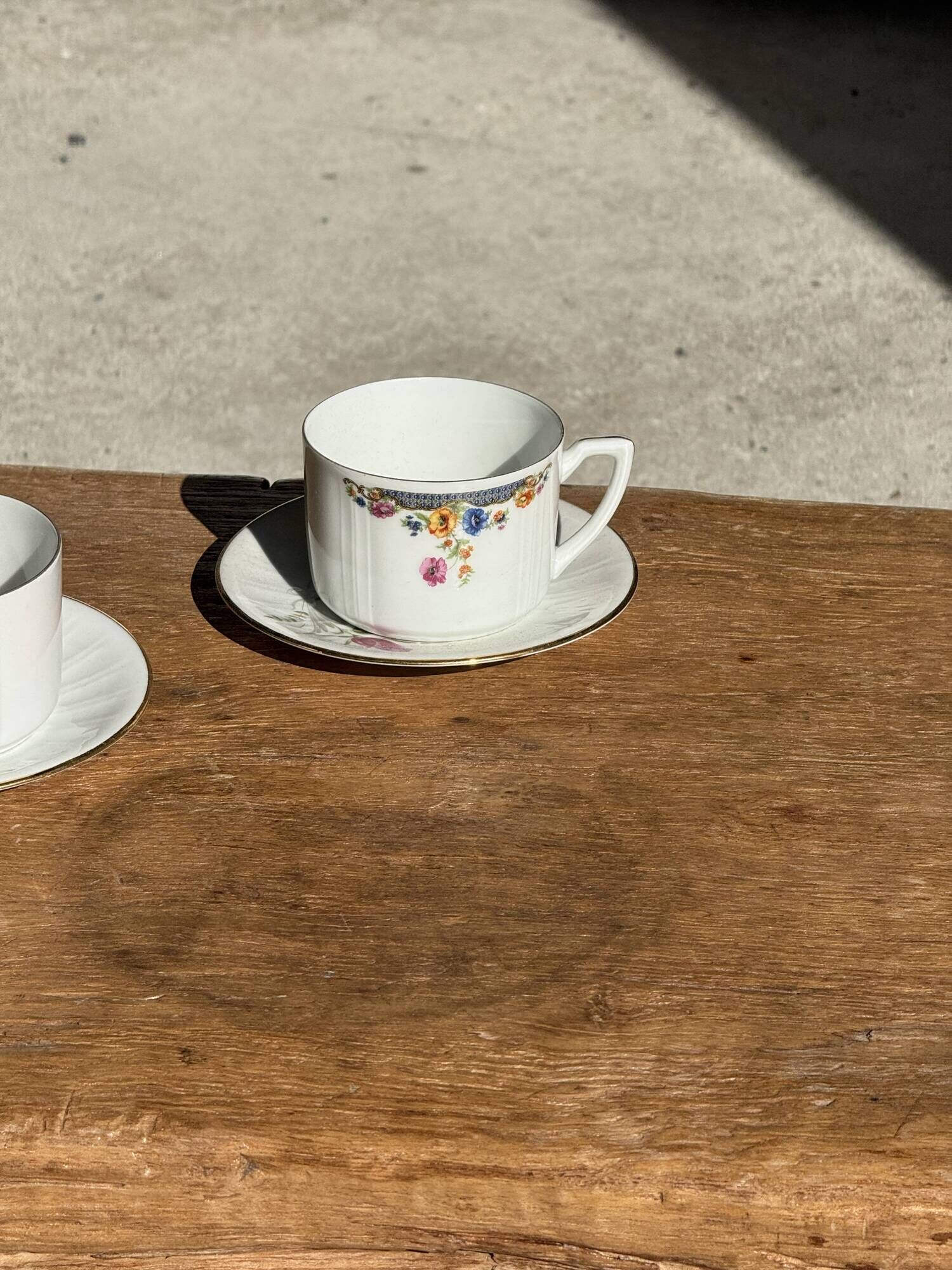 Pair of white porcelain cups from ADP France with a floral pattern and their s