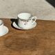 Pair of white porcelain cups from ADP France with a floral pattern and their s