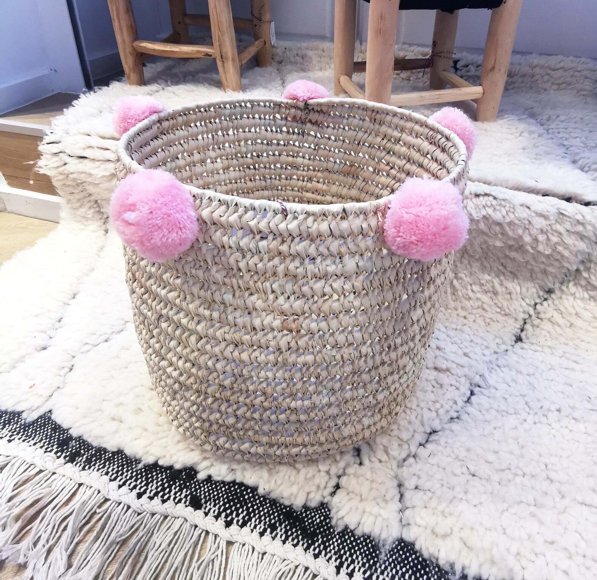 Moroccan basket with pale pink pompoms made of palm fiber