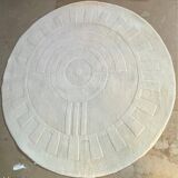 Round ecru rug with geometric relief patterns in wool