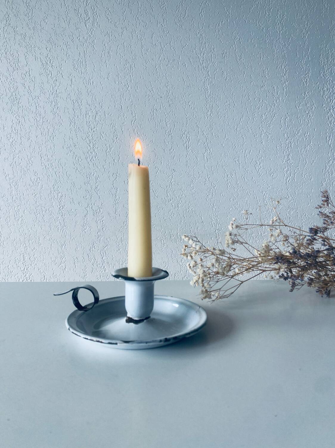 Old candle holder in white enameled metal