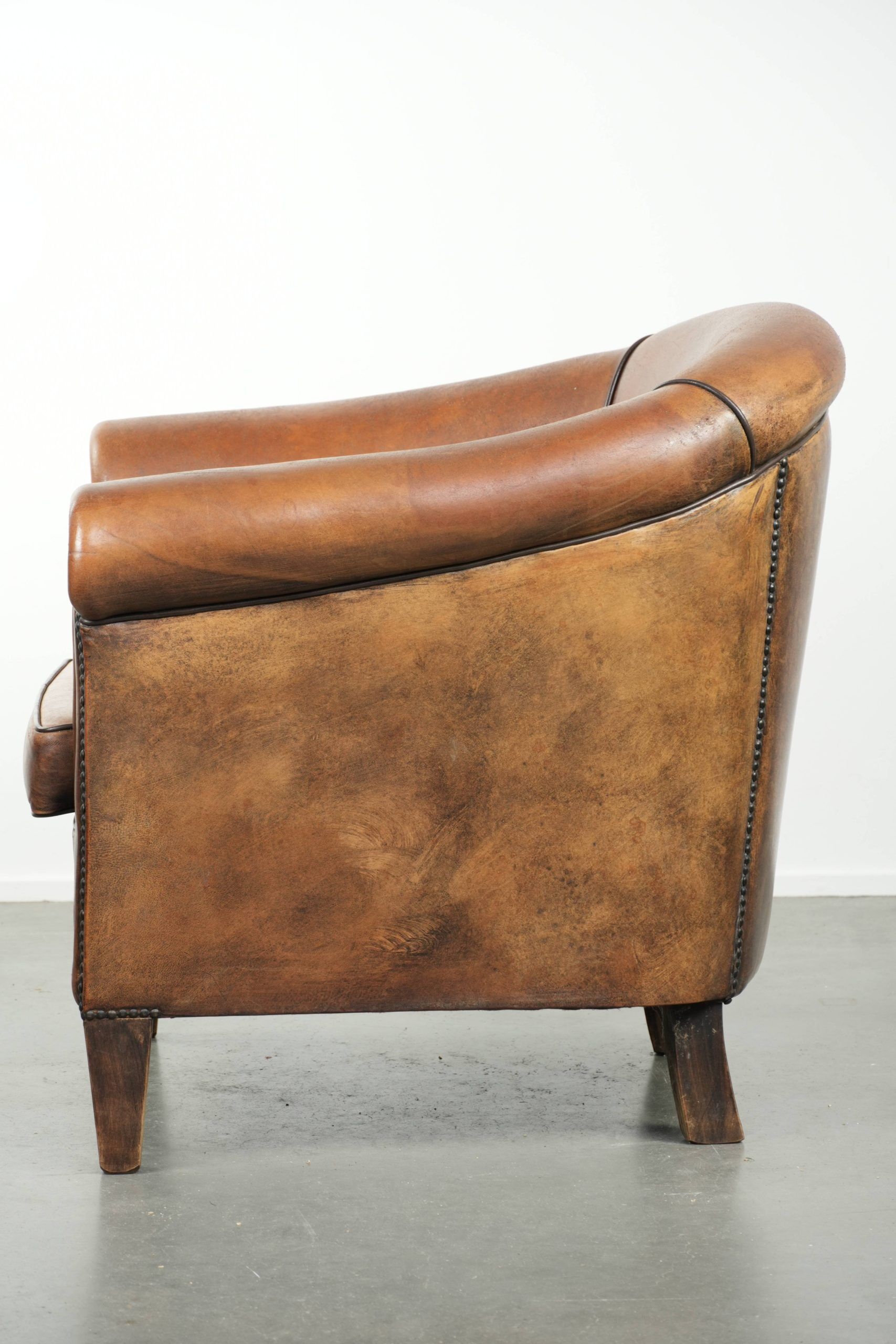 Sheepskin club armchair with beautiful patina and finish with black piping