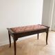 Antique wooden storage bench with red fabric.