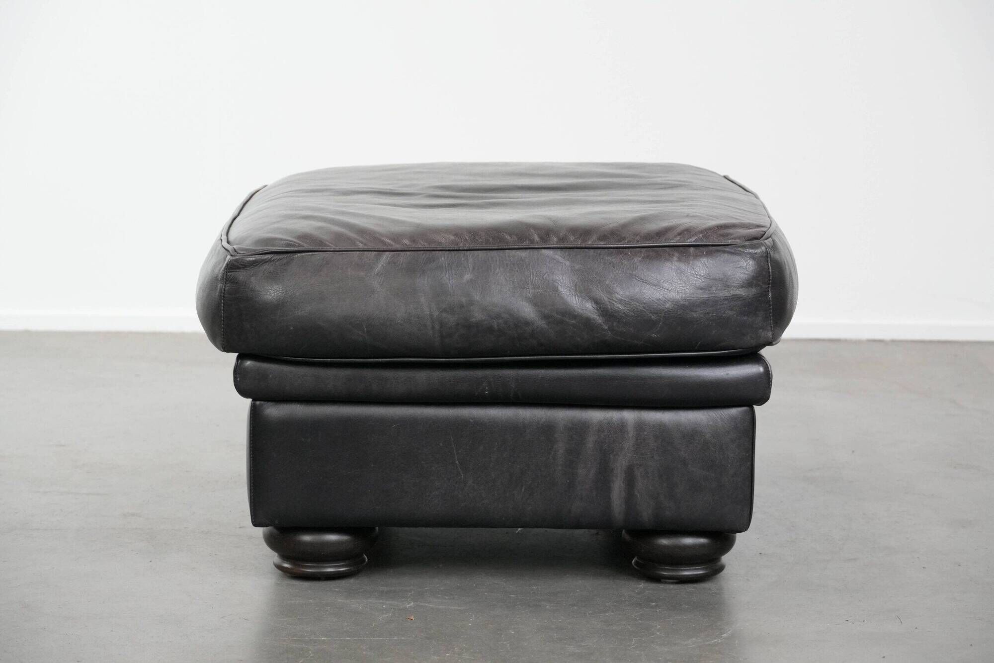 Set of a black cowhide leather Chesterfield armchair and matching ottoman