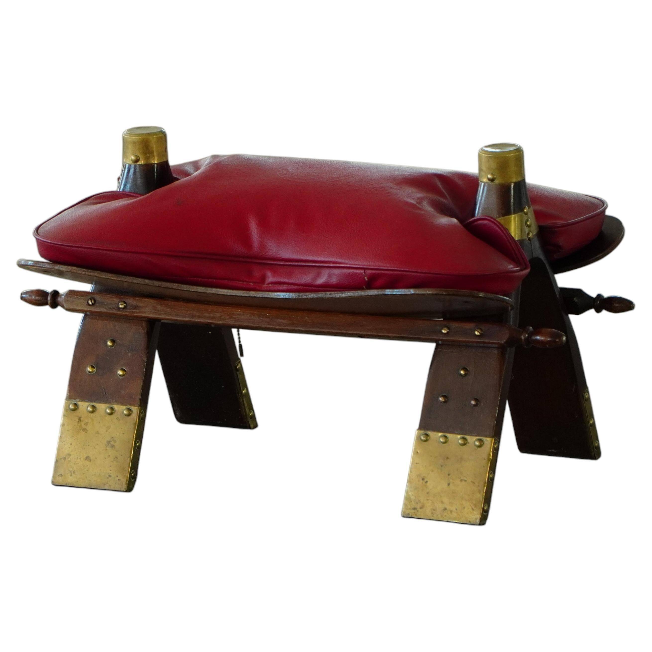 Moroccan stool in the shape of a camel saddle, stained wood, brass and leather, North Africa, 1980.