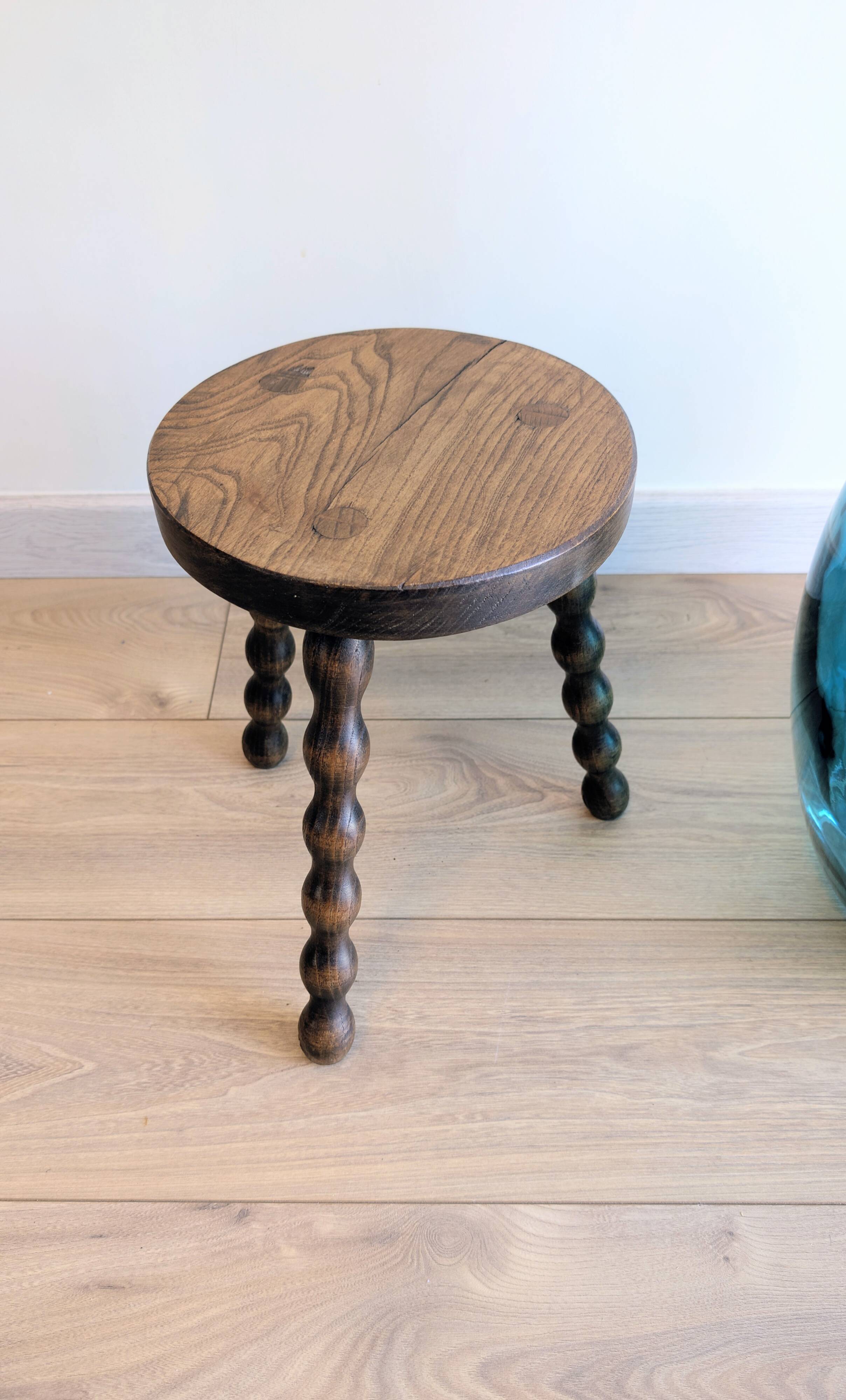 Small wooden tripod stool with turned legs, country style.