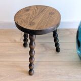 Small wooden tripod stool with turned legs, country style.