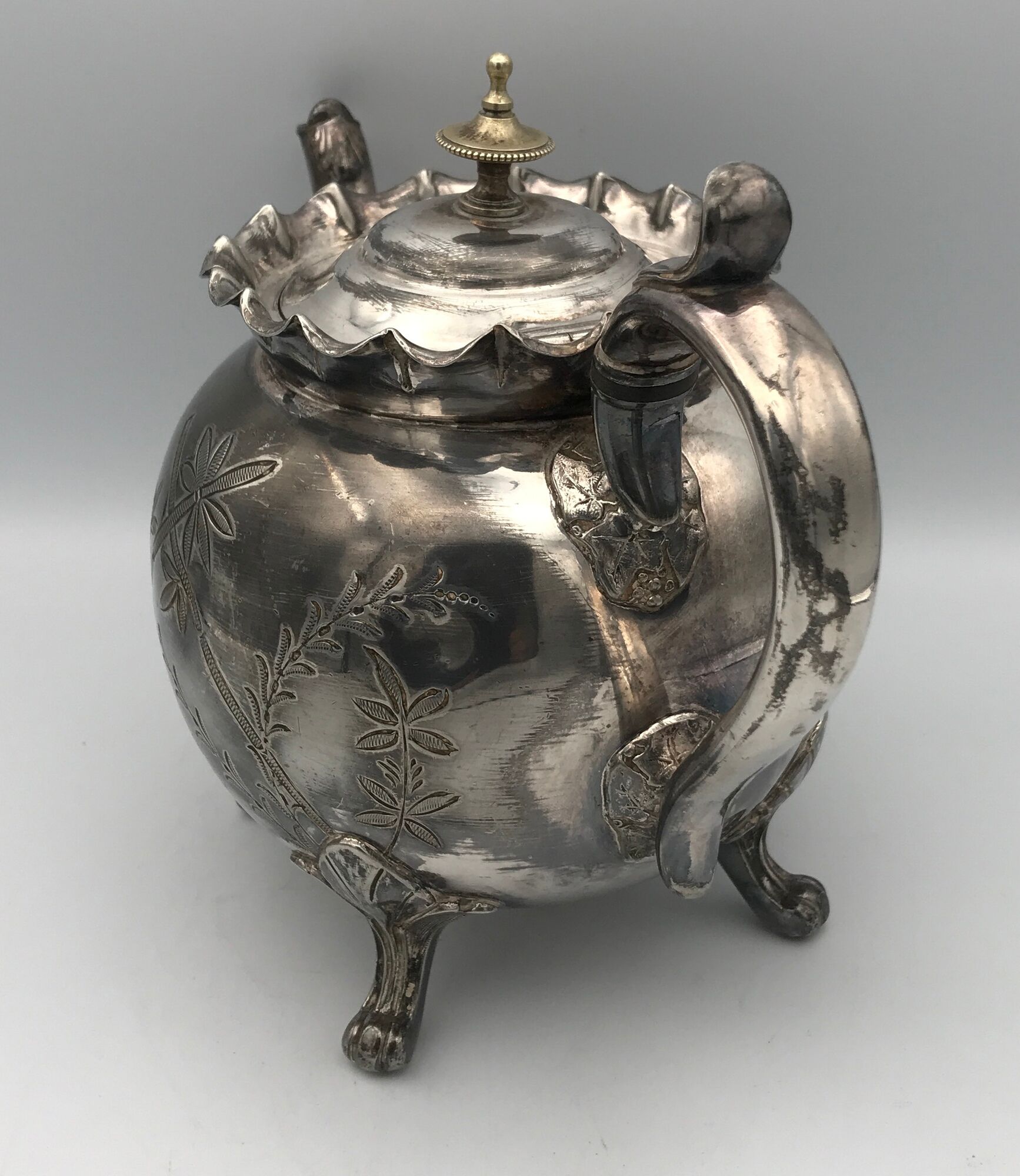 Old teapot pourer in silver metal decorated with foliage and butterflies
