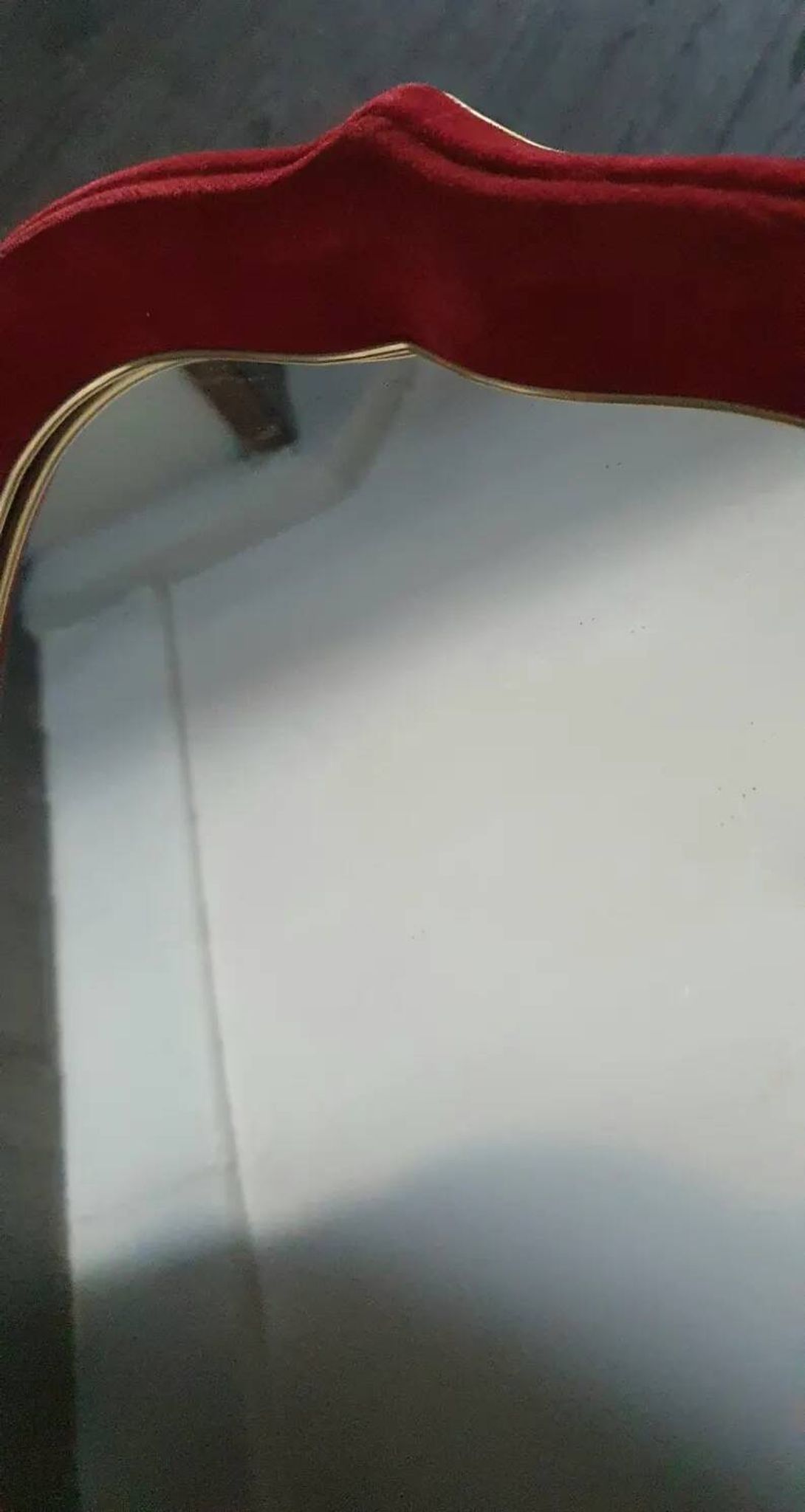 Vintage mirror with a scalloped shape in burgundy velvet and a golden trim.
