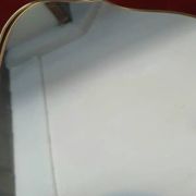 Vintage mirror with a scalloped shape in burgundy velvet and a golden trim.
