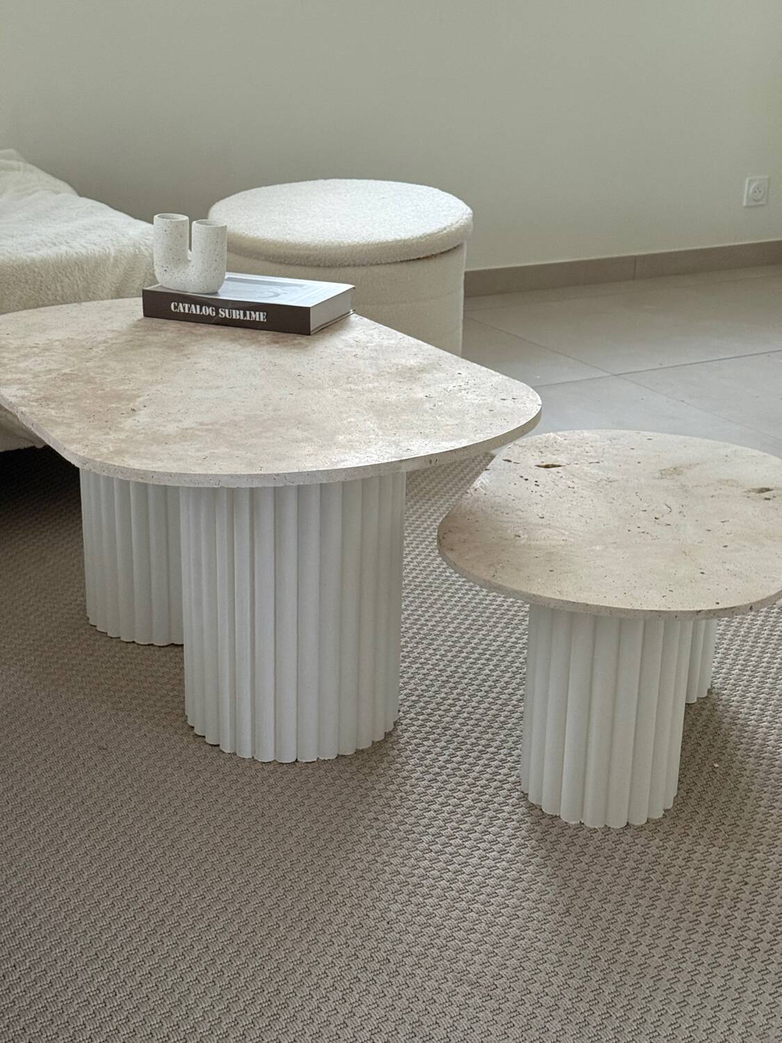 Oval coffee table duo travertine and white fluted wooden legs.