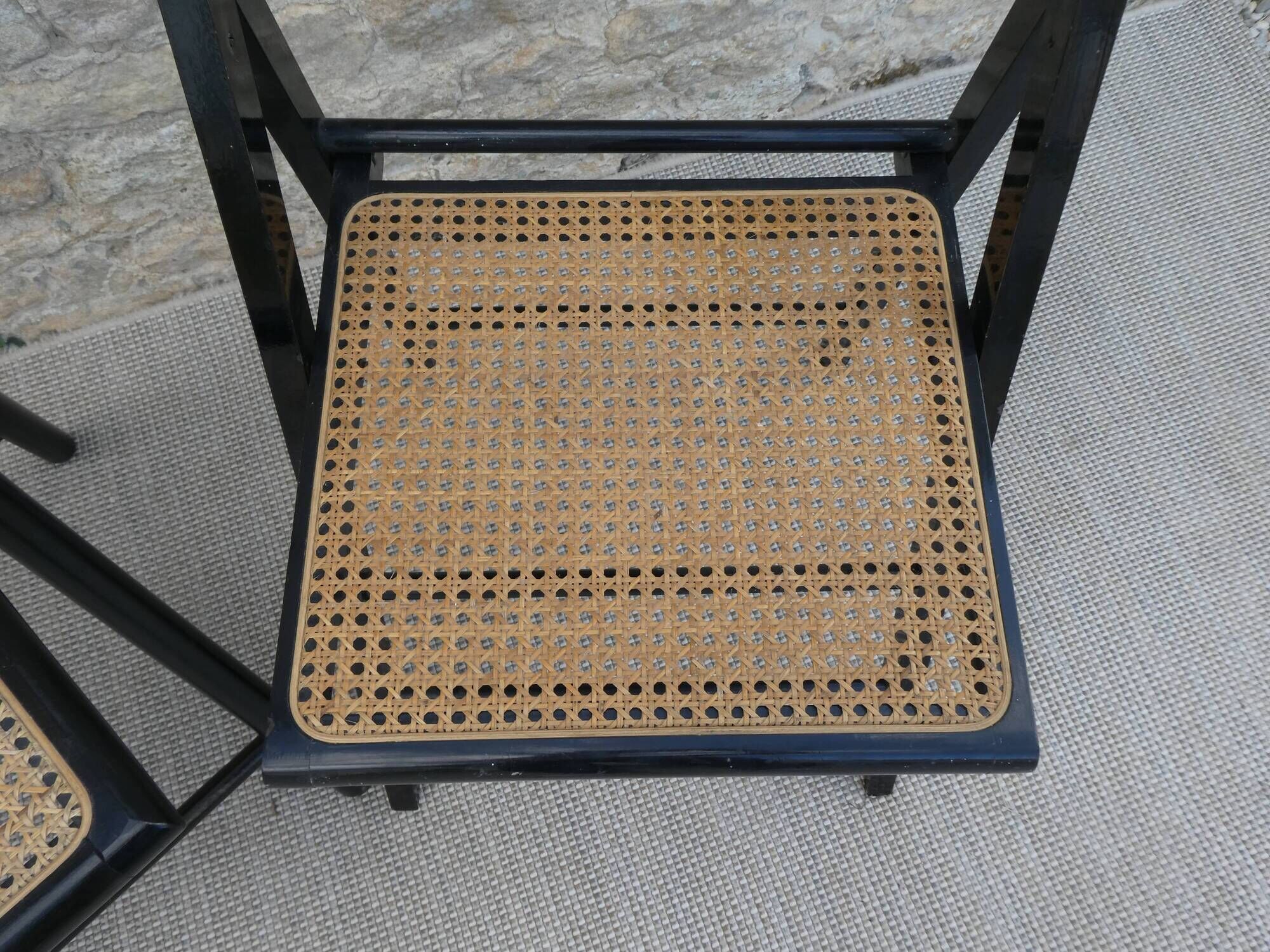 Paire de chaises pliantes en bois noirci et assise cannée