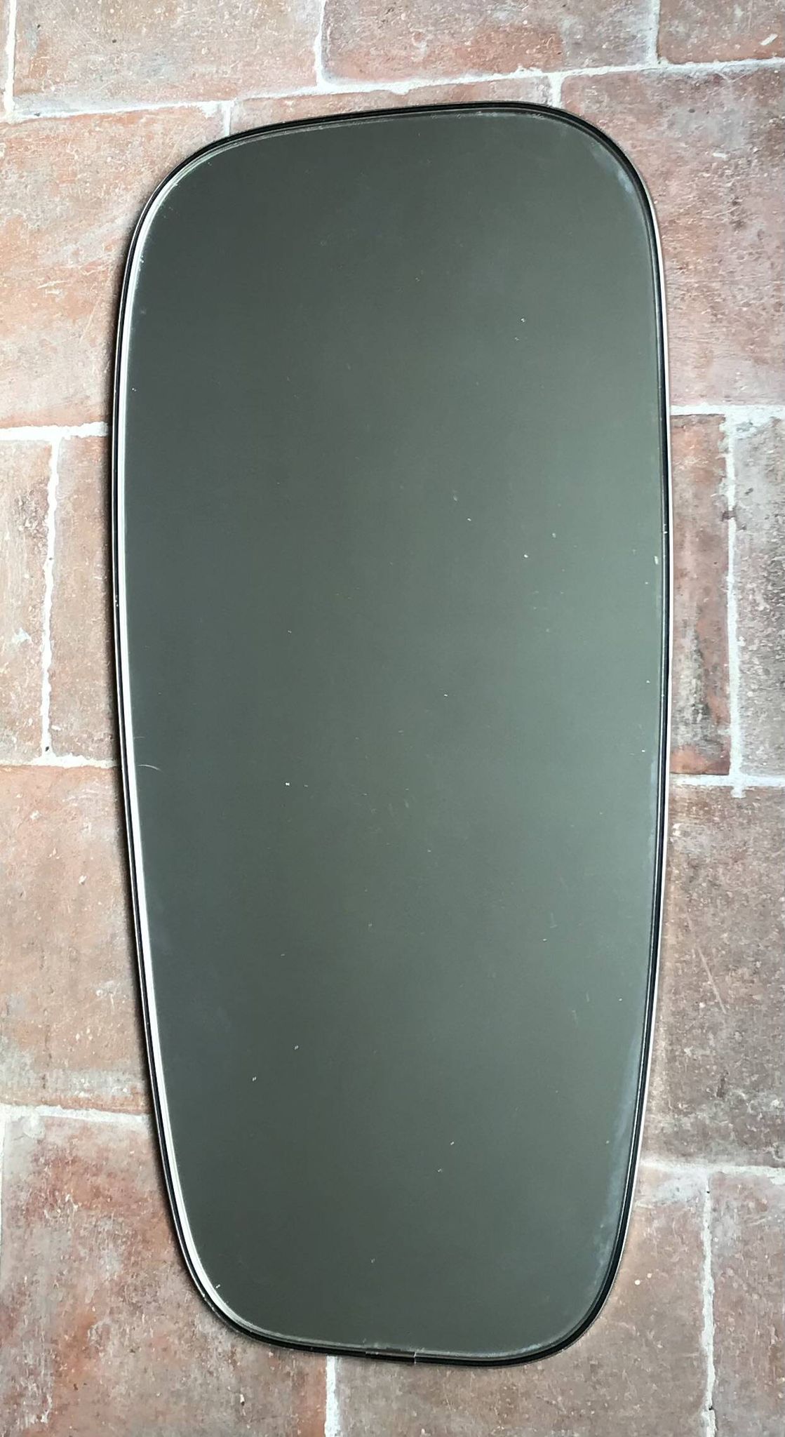Vintage 1960 free-form mirror known as a retro mirror with a gold and black metal trim.