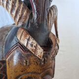 A large Senufo mask made of colored wood, decorated with an anthropomorphic figure