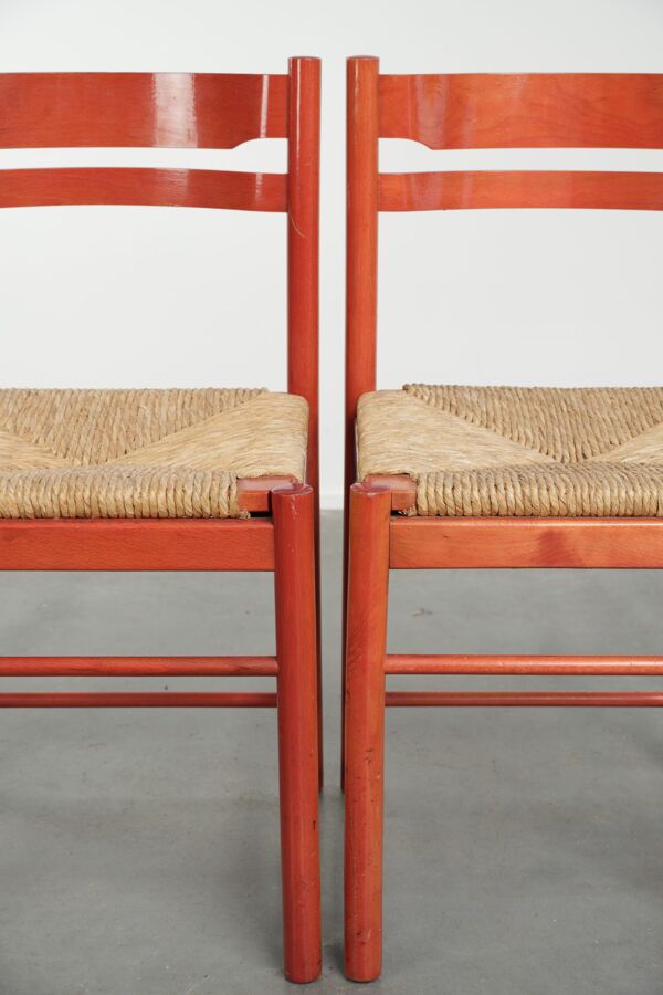 Ensemble de deux chaises en bois vintage rouges des années 1970 avec des sièges en rotin tressé.