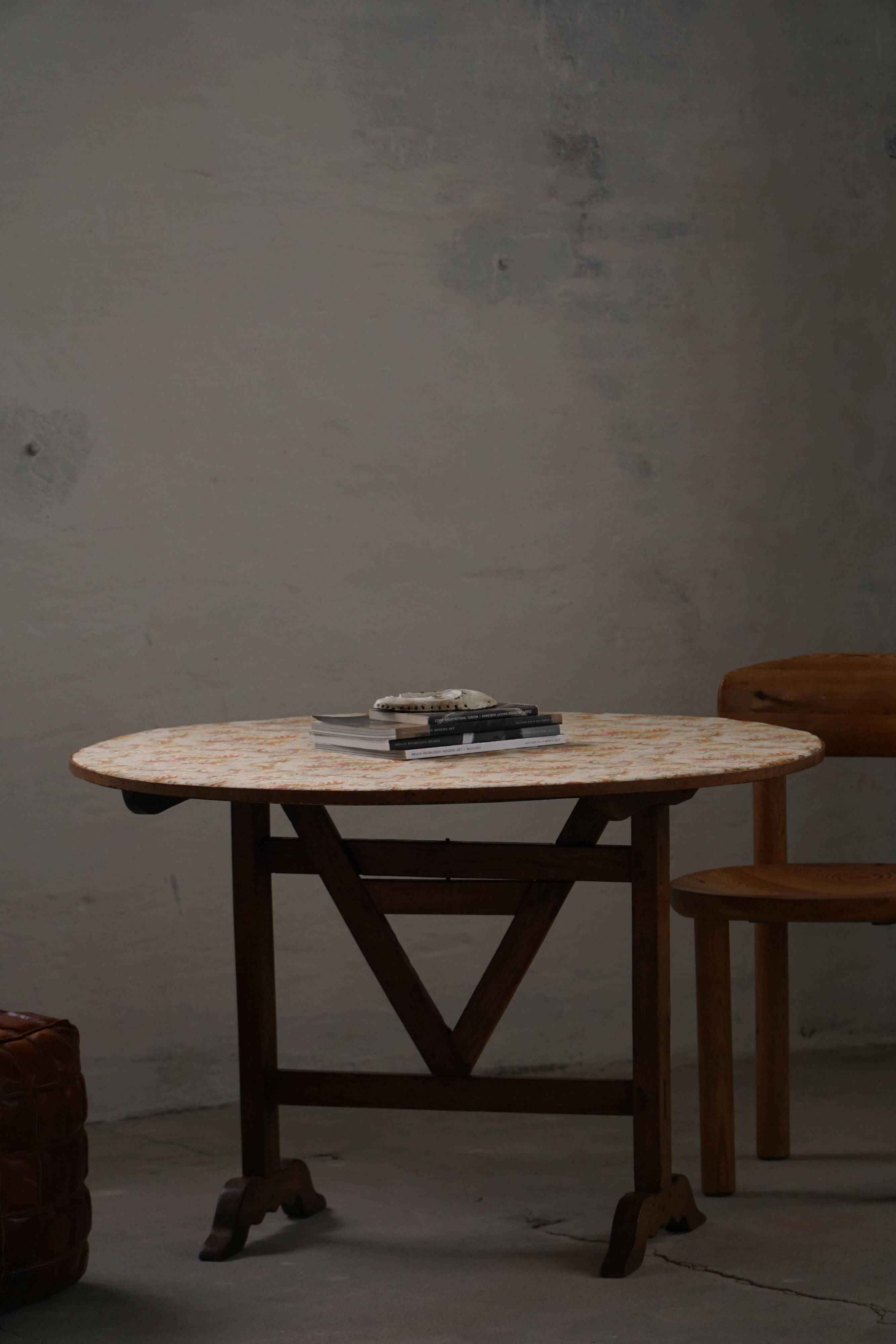 19th-century French round wine table with an adjustable top and floral textile surface.