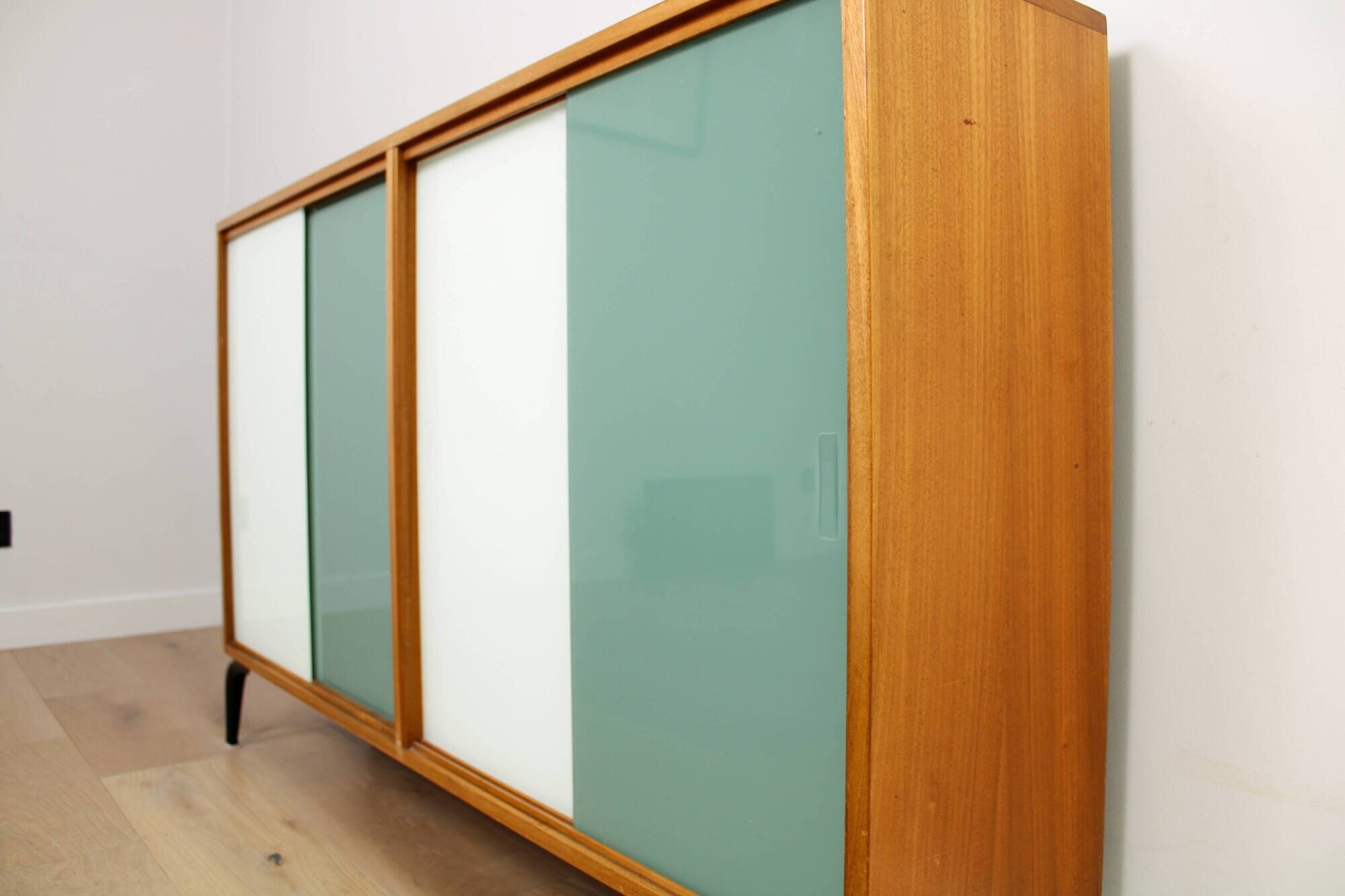 A vintage mid-century bookshelf/sideboard with green and white sliding door