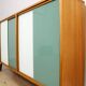 A vintage mid-century bookshelf/sideboard with green and white sliding door