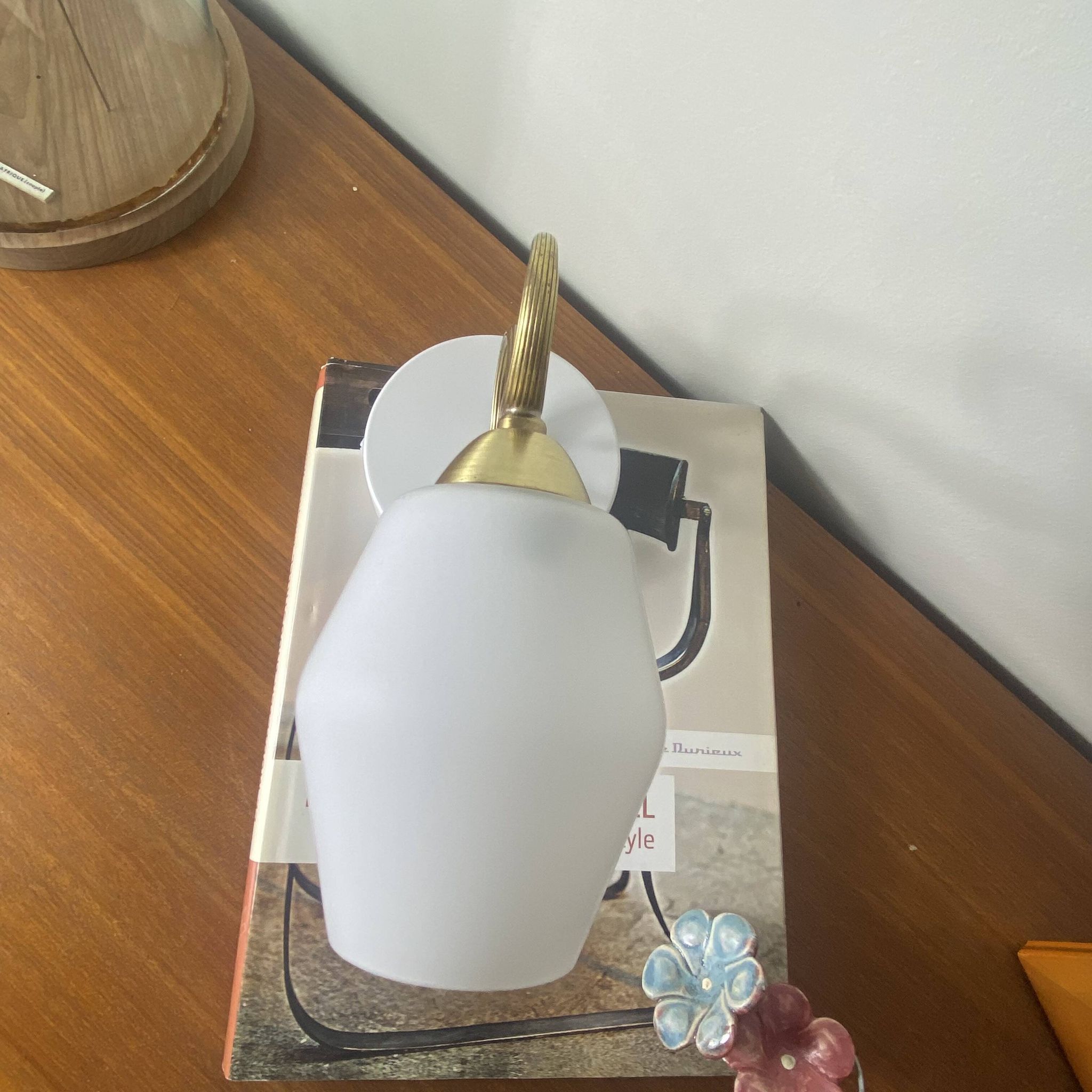Swan neck wall light in brass with a white glass shade.