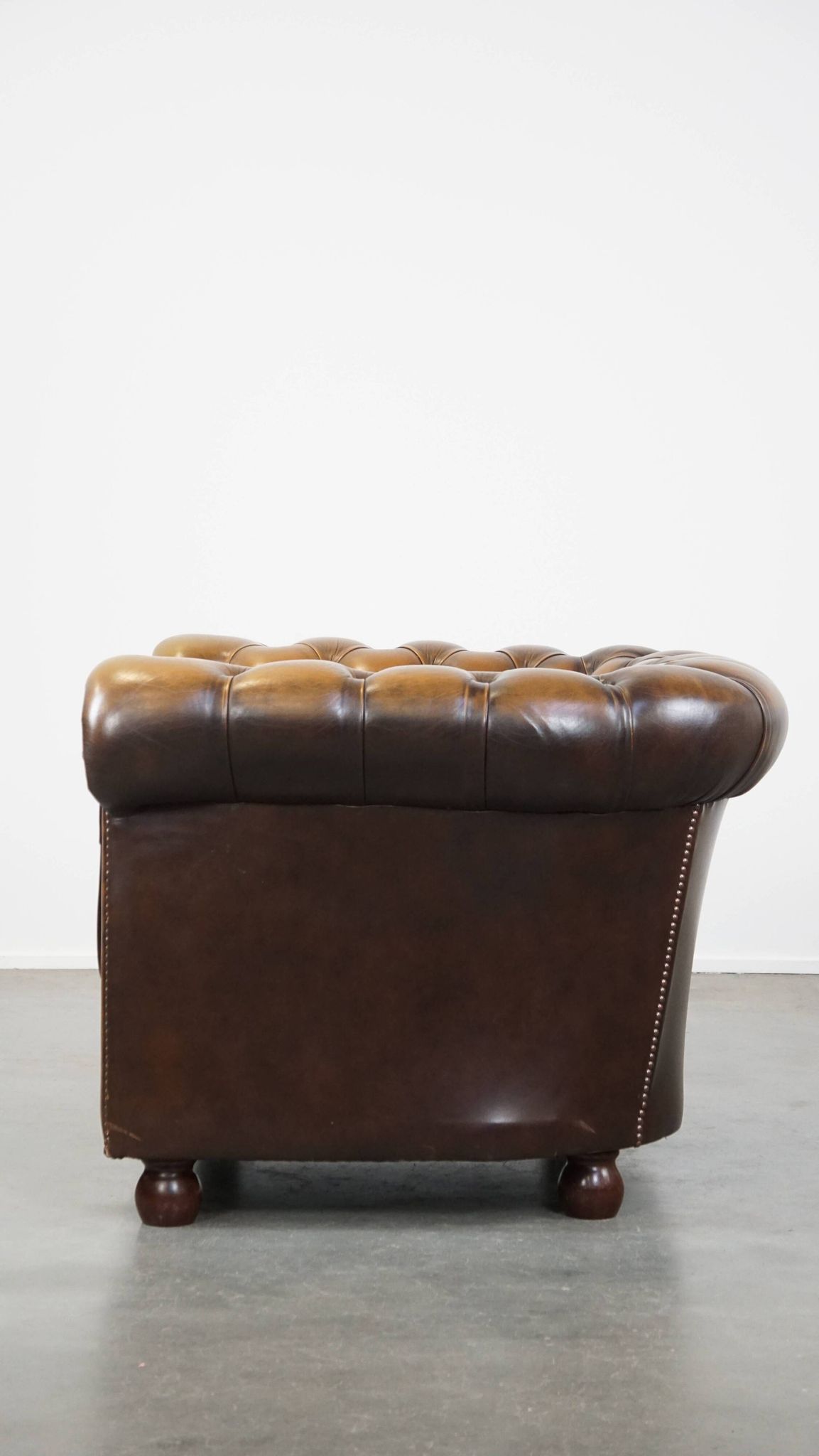 A well-maintained cowhide leather English Chesterfield armchair