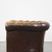 A well-maintained cowhide leather English Chesterfield armchair