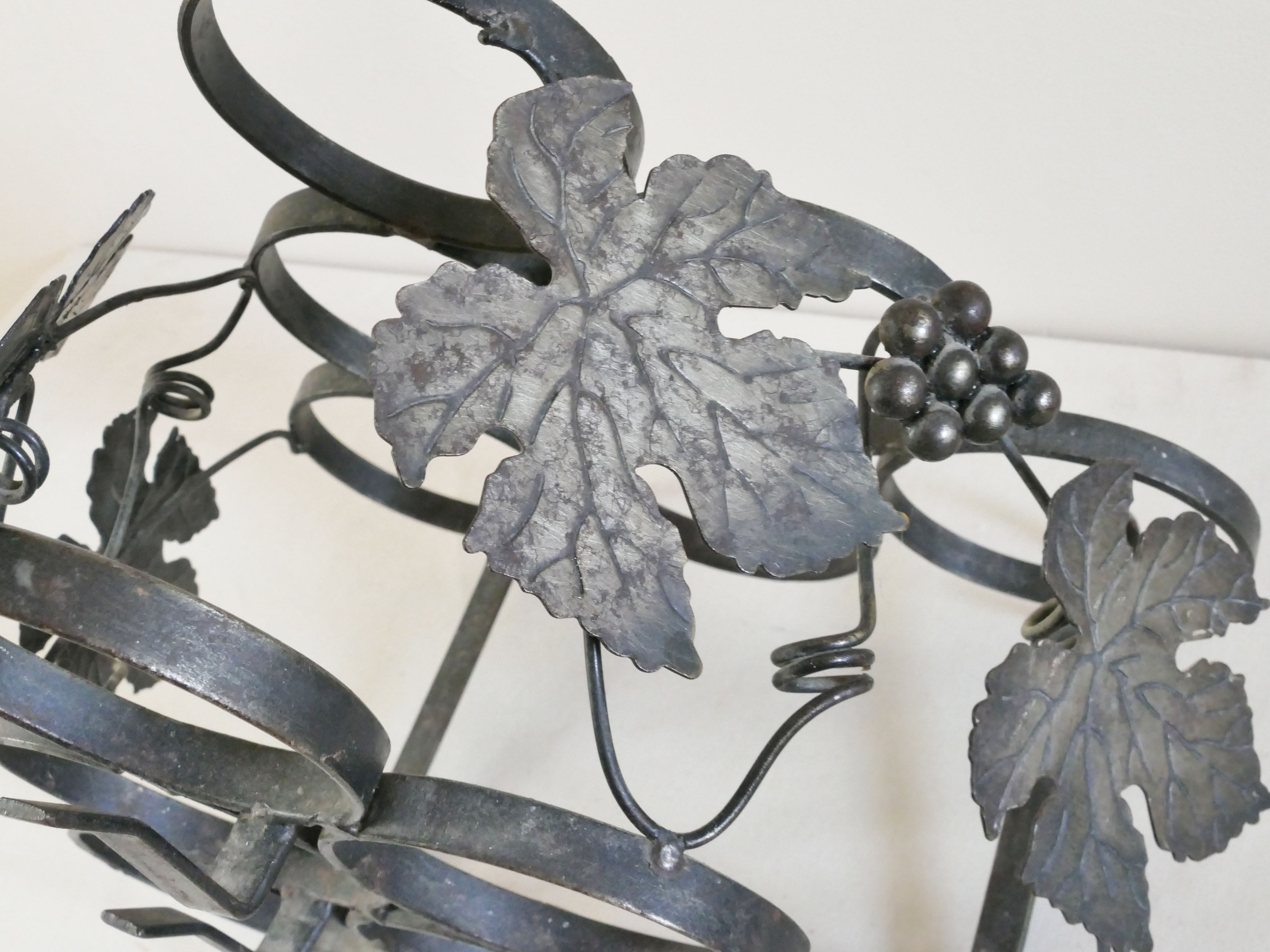 Vintage black wrought iron bottle holder decorated with vine leaves