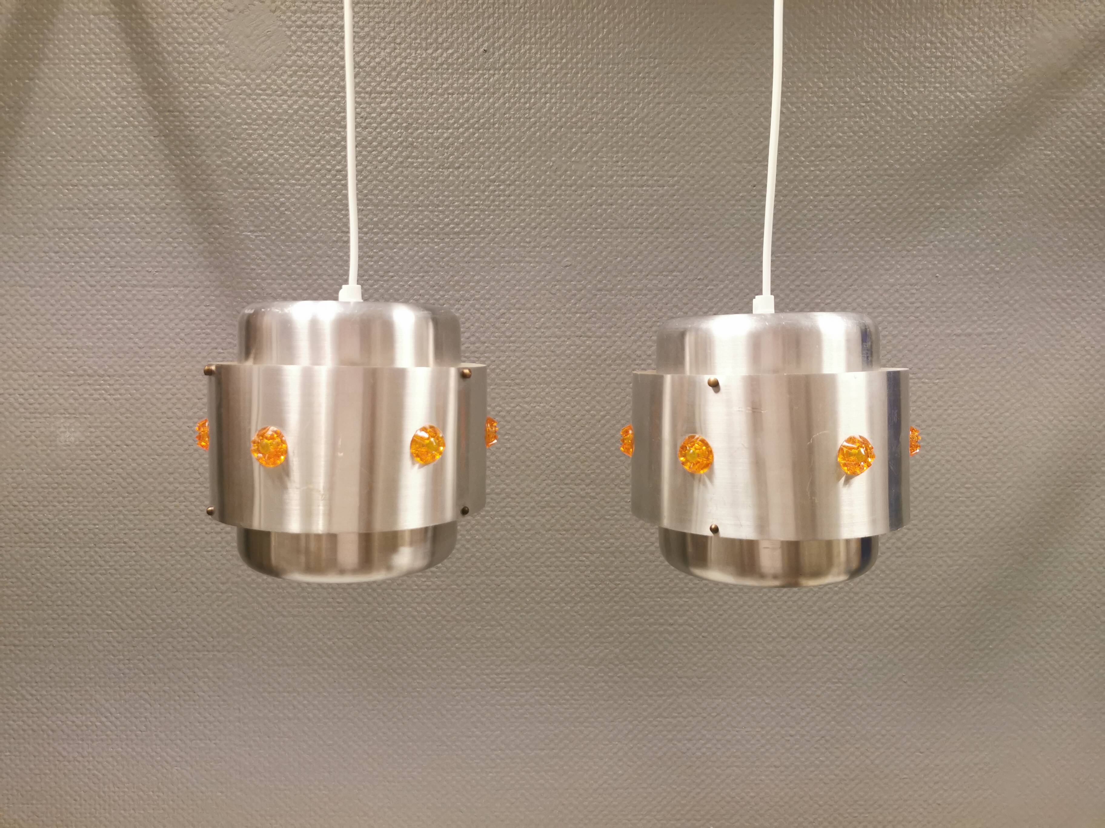 Two Space-Age hanging lamps, in silver-coloured aluminium with orange prisms.