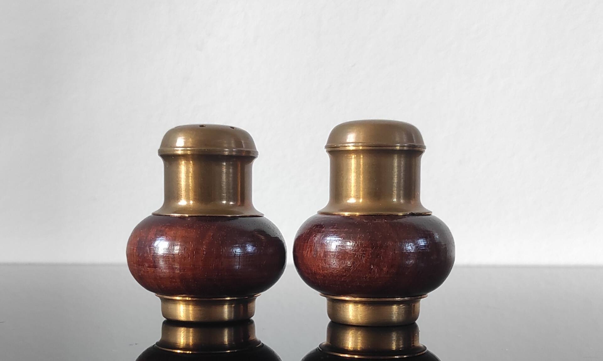 Vintage salt and pepper shaker duo in brass and turned wood.