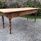 Antique Louis Philippe style farm table in solid cherry wood with 2 drawers and turned base.