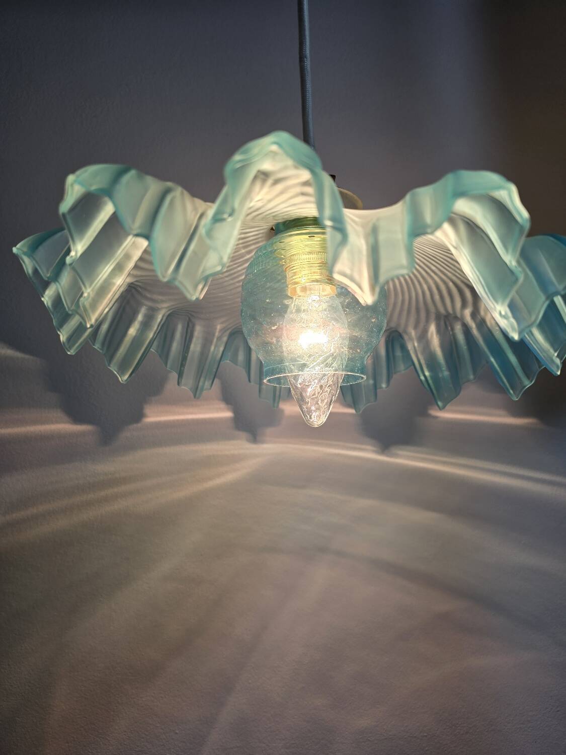 Suspension lampshade with scalloped edges in blue and its interior decoration.