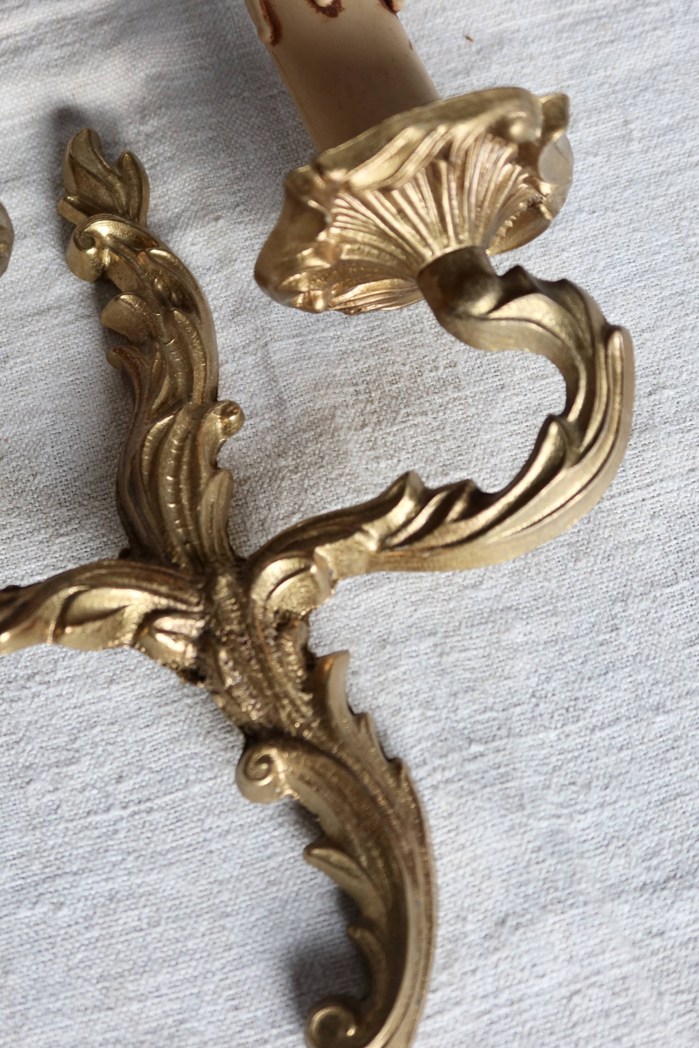 Vintage wall sconce in gold metal with two arms in classic style.