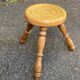 Vintage low tripod stool with carved light oak legs.