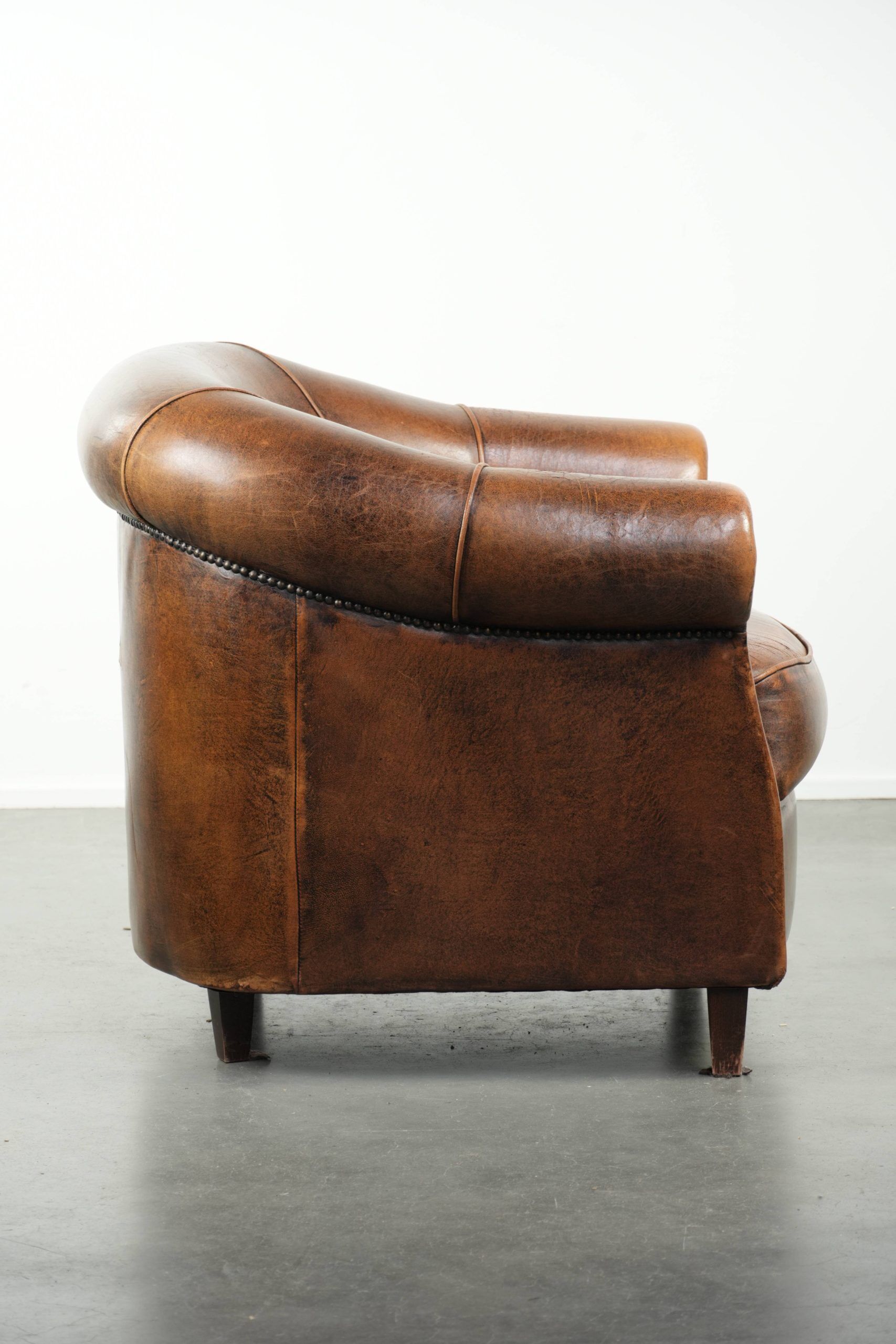 Fauteuil club en cuir de peau de mouton avec un coussin de siège fixe.