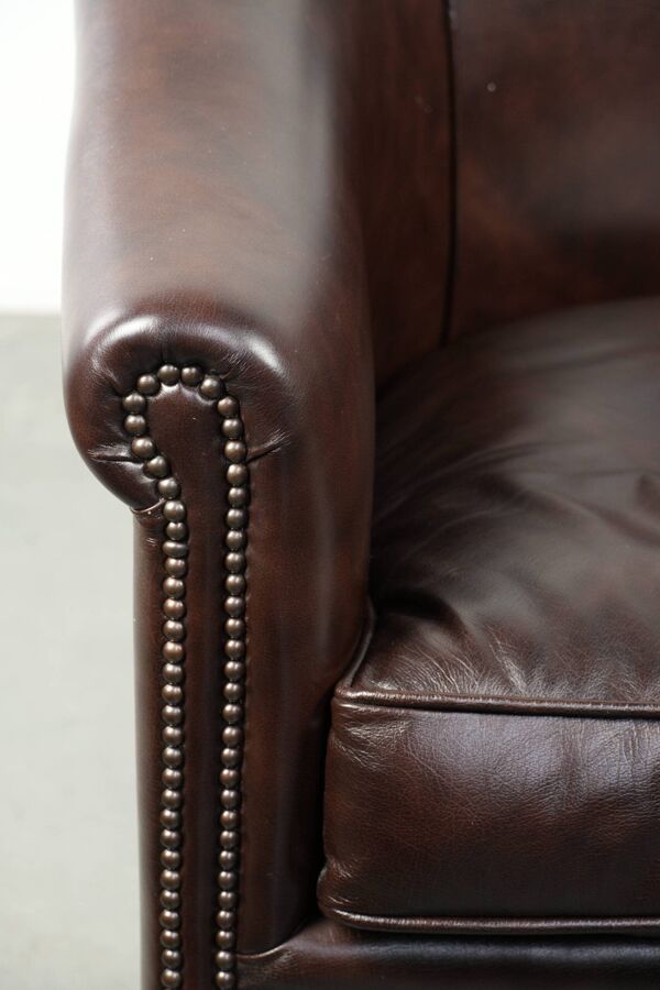 Fauteuil club en cuir noir en bon état avec un design anglais.