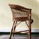 Woven rattan armchair with armrests.