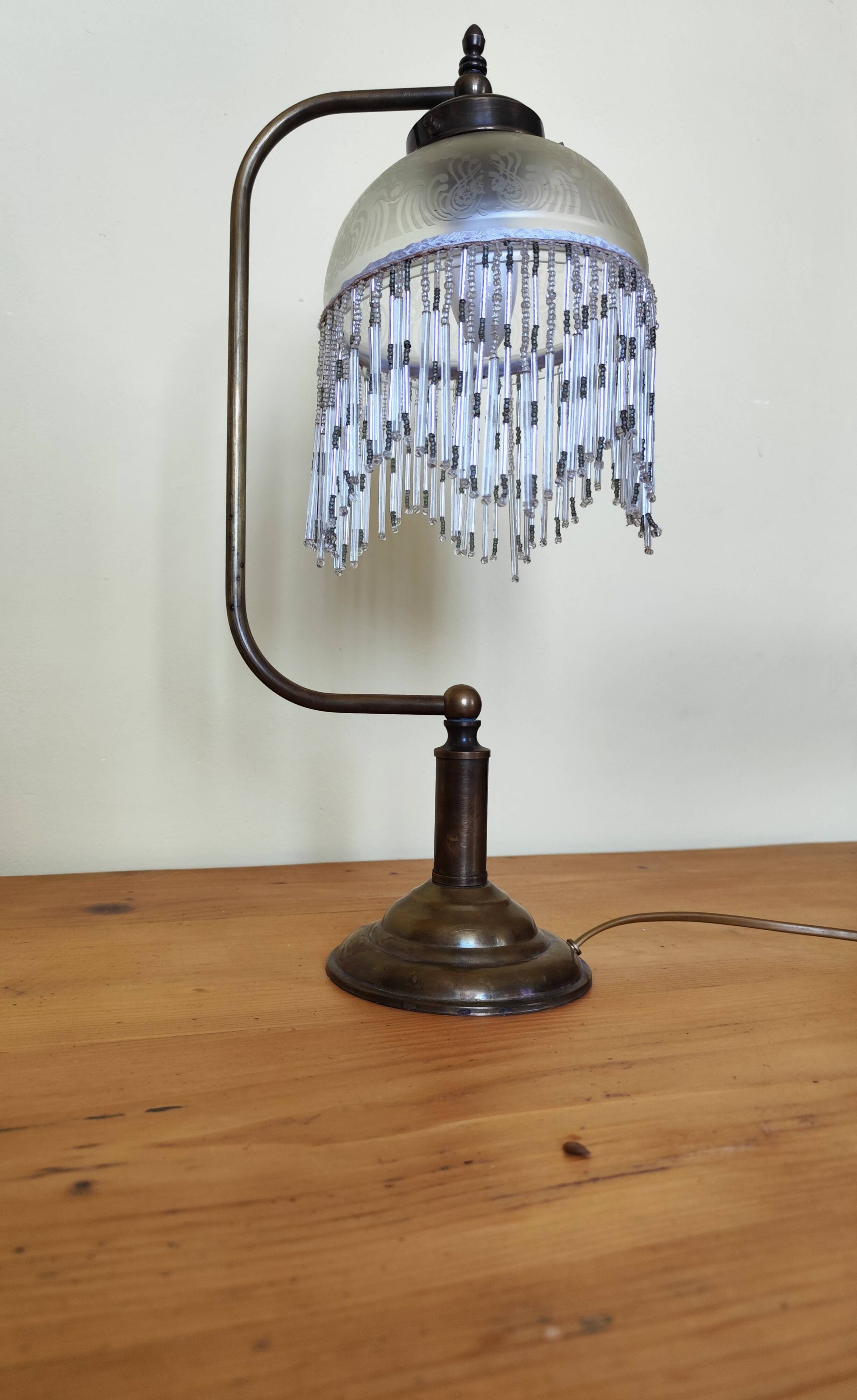 Retro brass lamp with a glass shade and bead fringes.