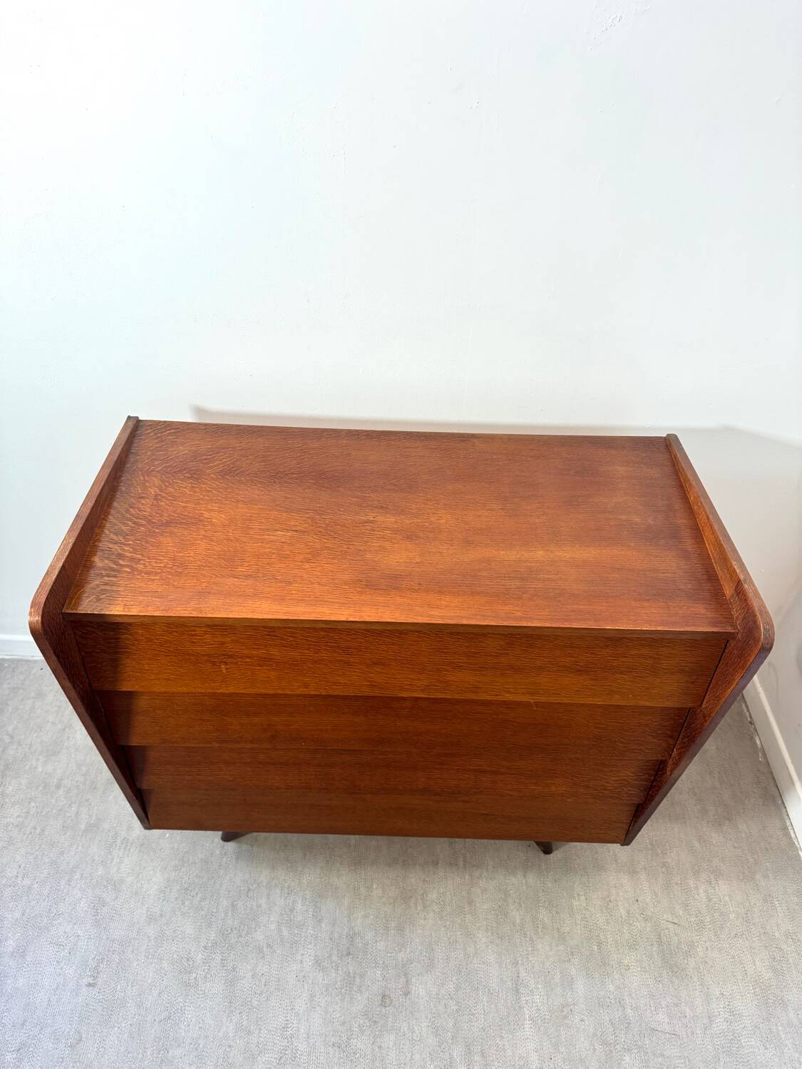 Vintage wooden chest of drawers with tapered legs.